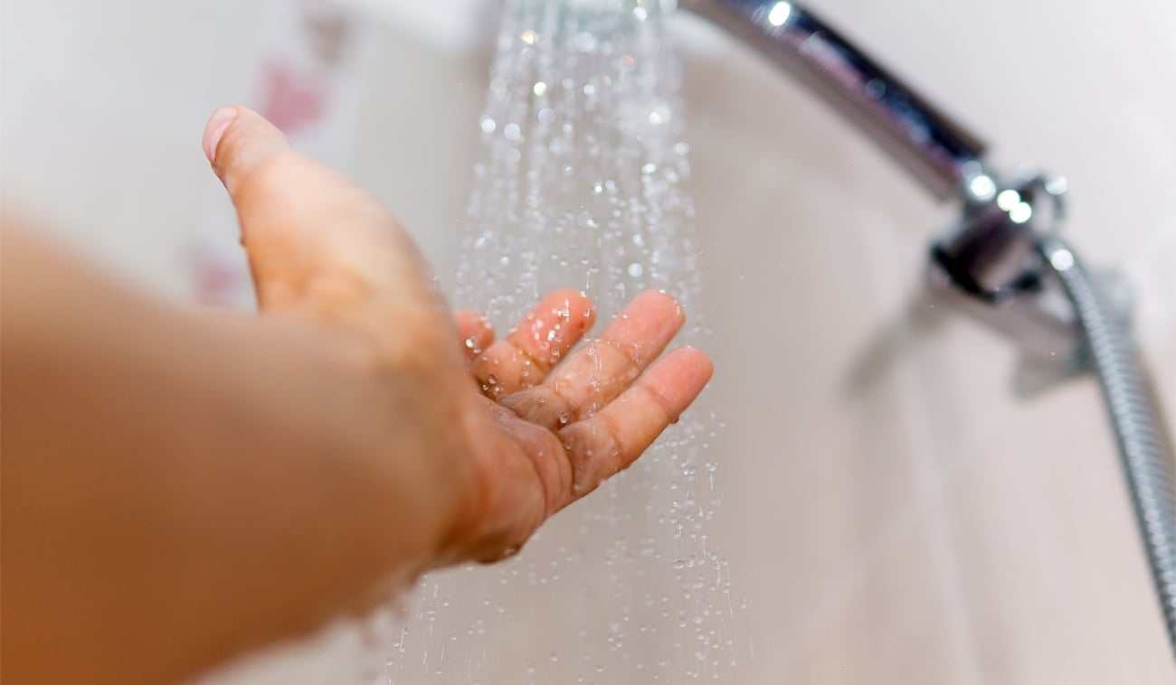 Agua caliente que cae desde la ducha hasta una mano