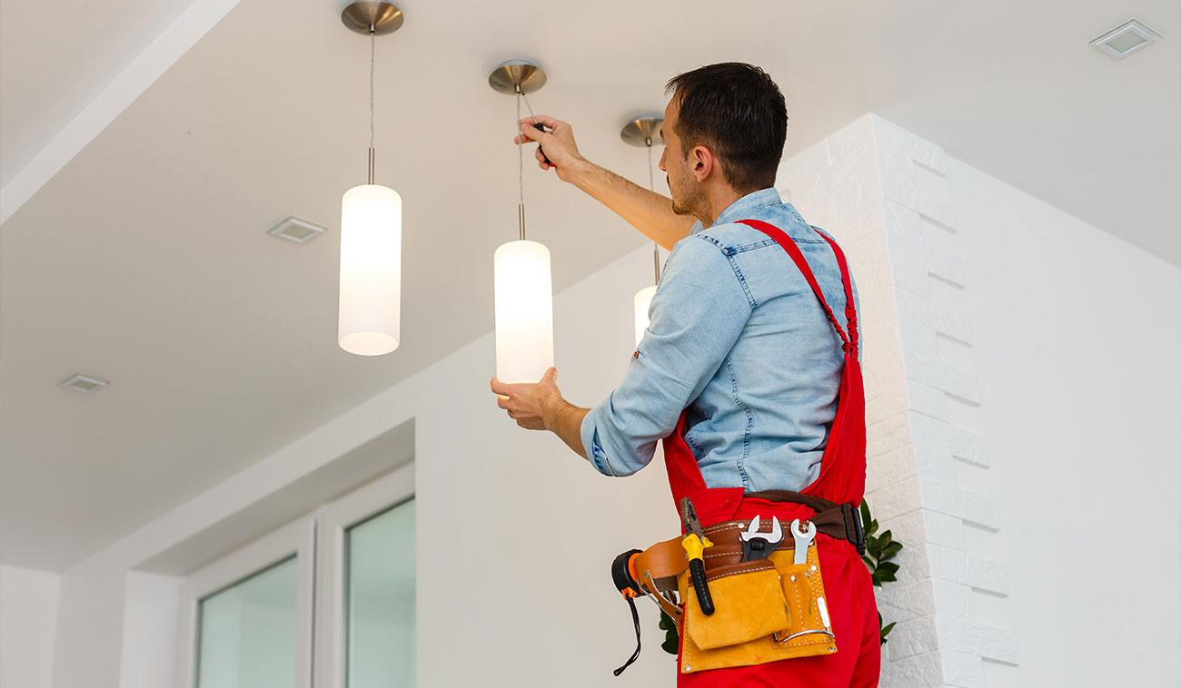 Instalador eléctrico poniendo una lámpara en el techo de una habitación