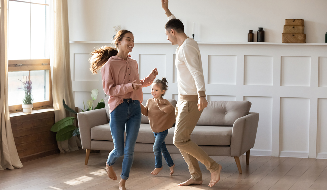 Familia baila en una habitación con piso flotante de color café claro.